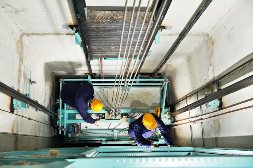 Men using an elevator maintenance checklist to perform a safety inspection