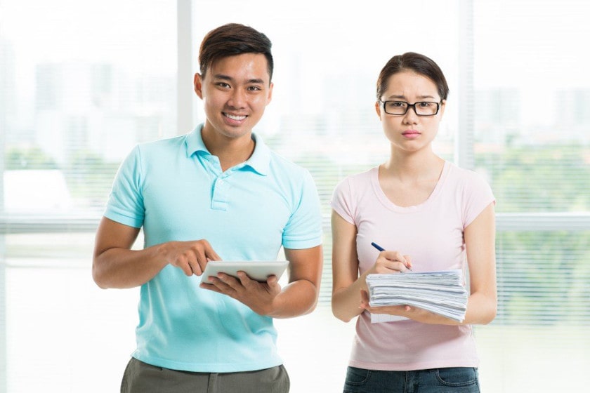 man with tablet next to woman with stack of paper