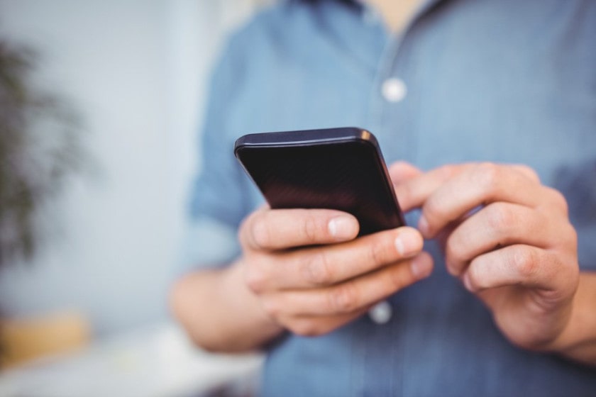 Midsection of businessman using cellphone while standing at creative office