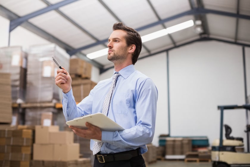 Side view of manager holding clipboard in a warehouse